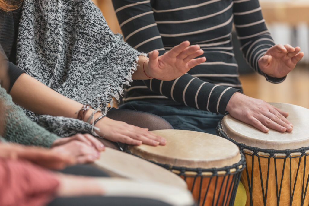 varias pessoas tocando instrumento de percussão, praticando a musicoterapia