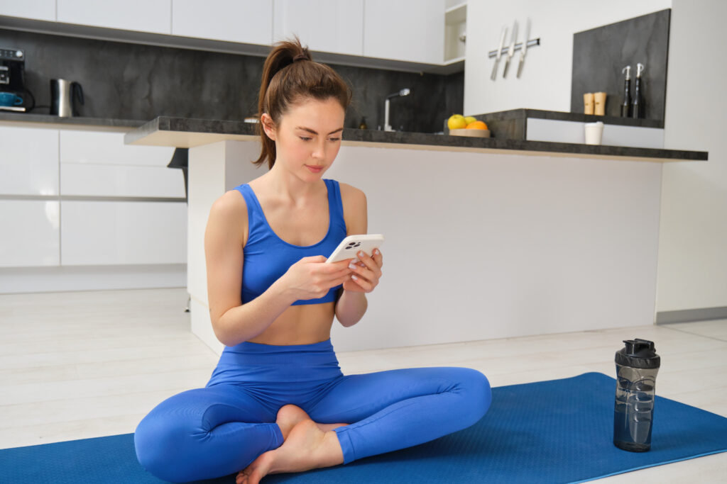 Mulher sentada usando celular para usar aplicativo de meditaçao