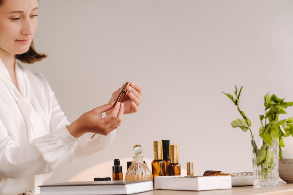 a aromaterapeuta menina é sentado dentro dela escritório e segurando uma garrafa do aromático óleos. lá estão essencial óleos em a mesa