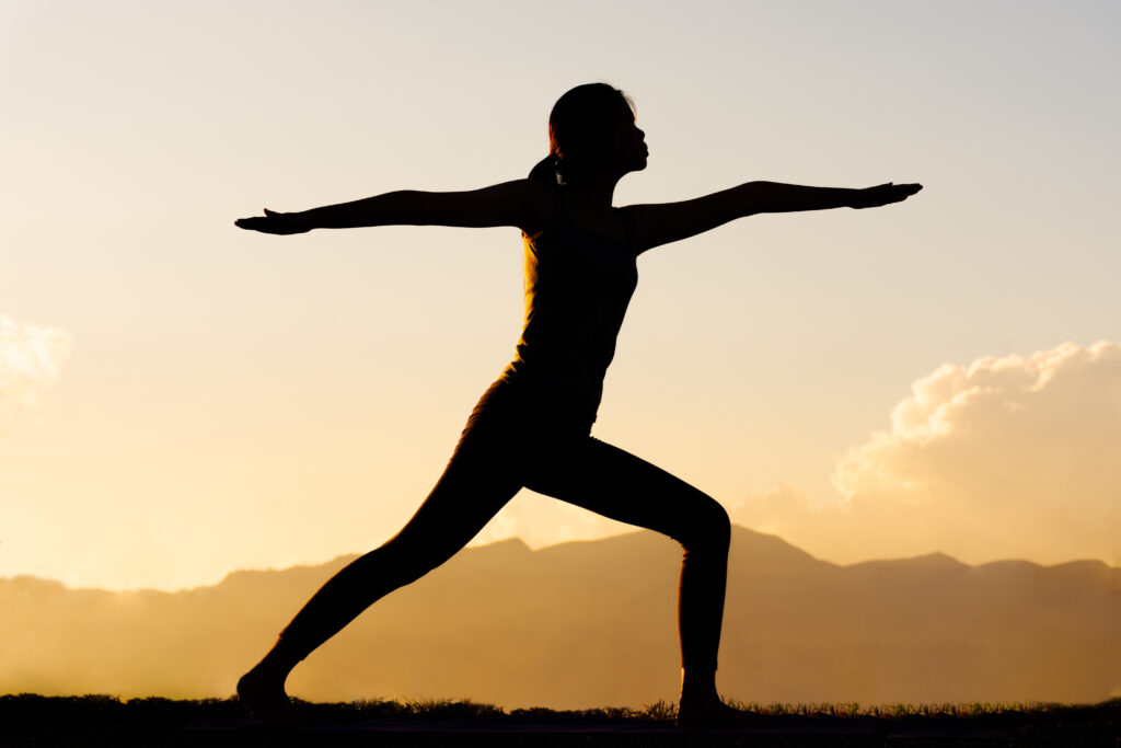 mulher praticando yoga ao por do sol