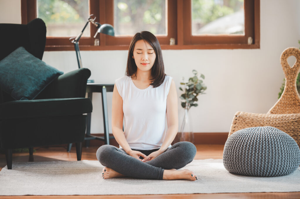 mulher jovem asiatica praticando meditação transcendental em casa