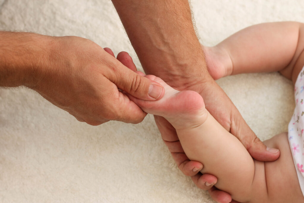 massagista fazendo massagem shantala para pé pequeno bebê