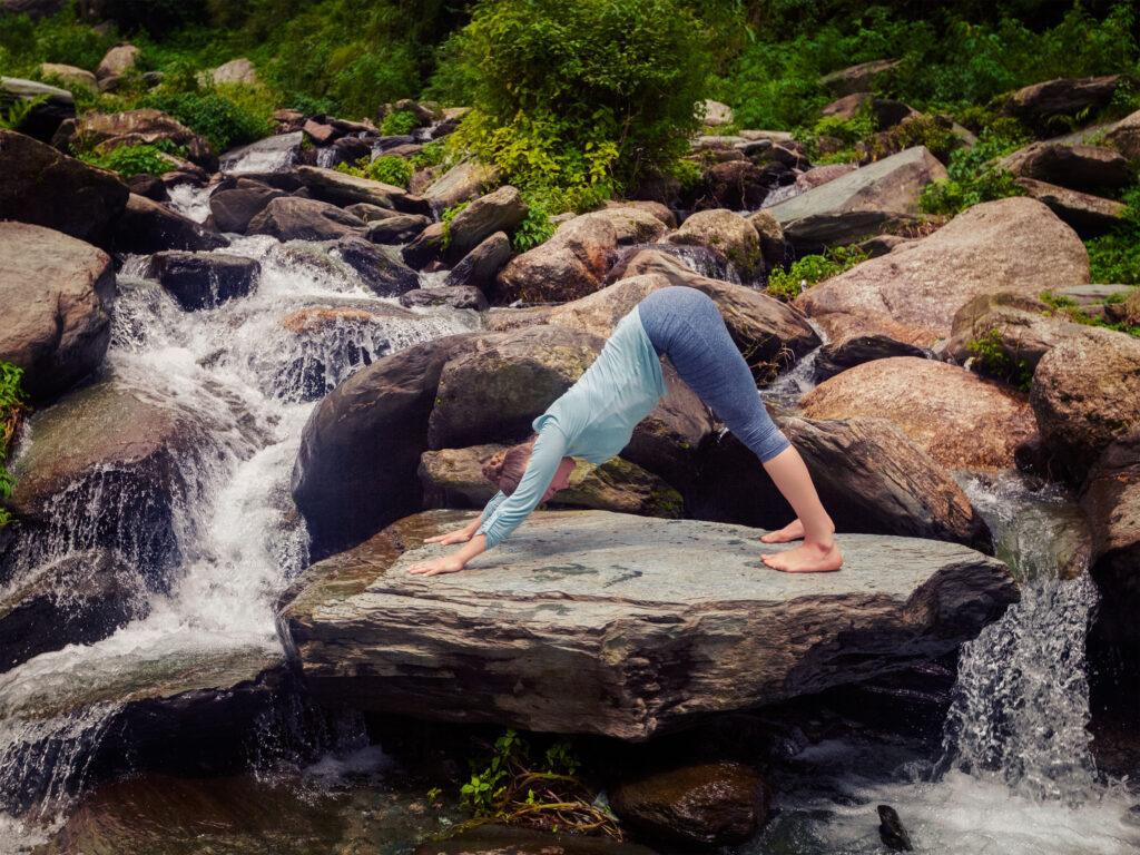 mulher praticando hatha yoga em uma cachoeira