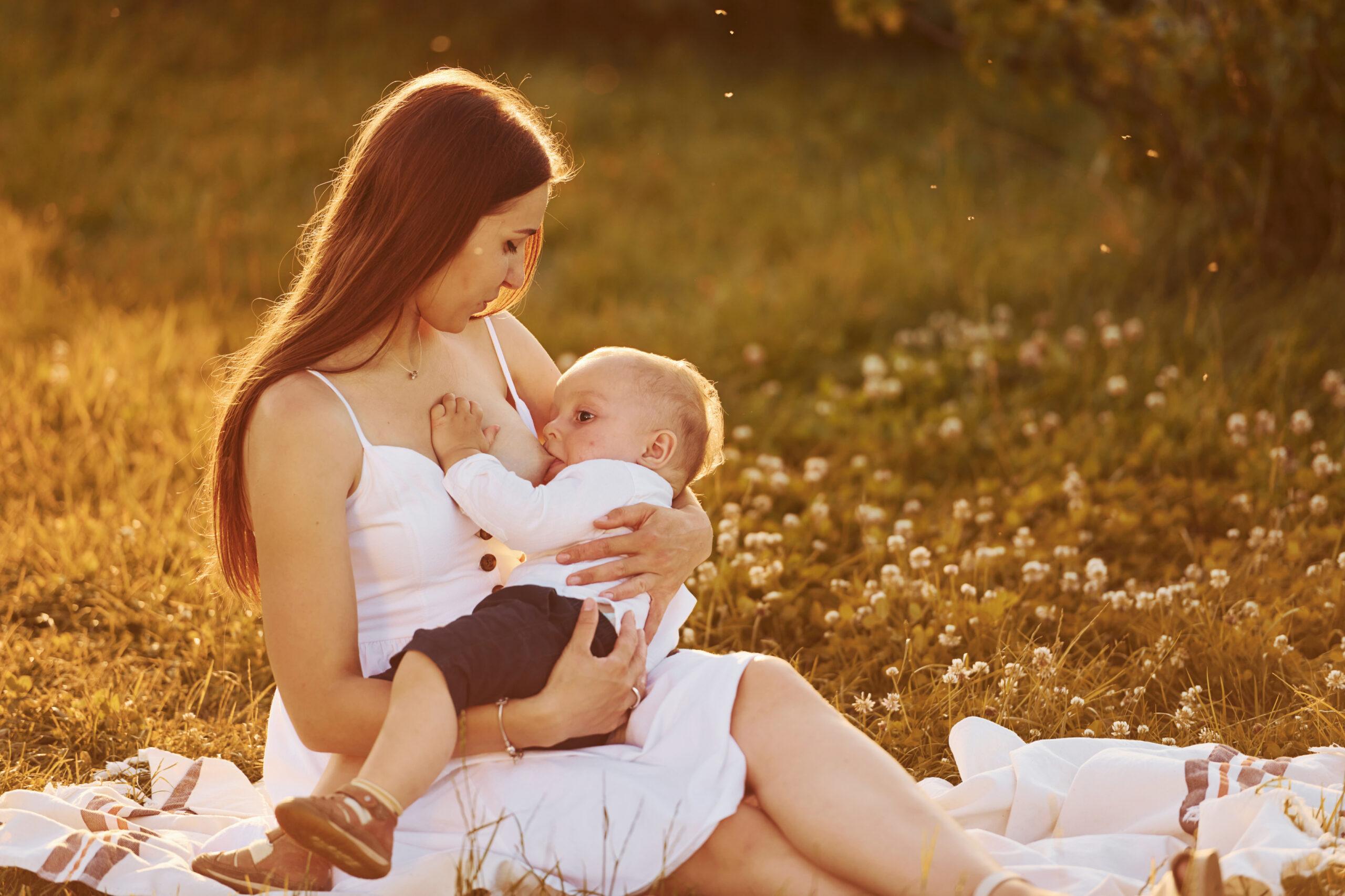 mãe amamentando bebe sentada em um jardim enfatizando a importancia do aleitamento materno